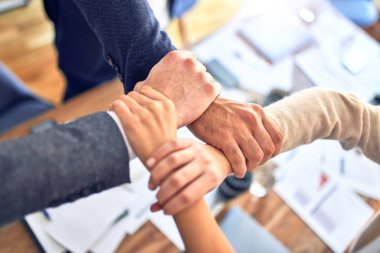 Bir grup işçi el ele tutuşup ofiste sembol oluşturuyorlar.