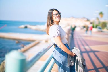 Mutlu ve kendinden emin gülümseyen genç ve güzel bir kadın. Kasaba caddesinde yüzünde gülümsemeyle dikilirken