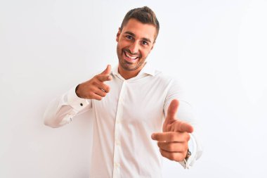 Soyutlanmış arka planda zarif gömlekler giyen genç yakışıklı iş adamı mutlu ve komik yüzlü parmaklarını kameraya doğrultuyor. İyi enerji ve titreşimler.