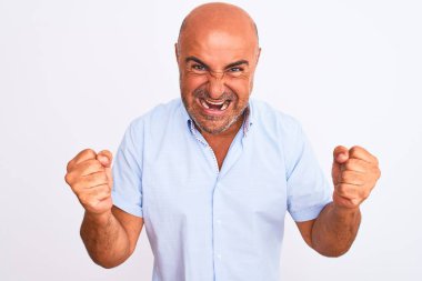 Orta yaşlı yakışıklı bir adam, izole edilmiş beyaz arka planda dikilmiş, şaşırmış ve şaşırmış bir şekilde kollarını kaldırıp, gözlerini açarak başarıyı kutluyor. Kazanan konsept.