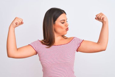 İzole edilmiş beyaz arka planda duran güzel genç bir kadının portresi gururla gülümseyen kol kaslarını gösteriyor. Fitness konsepti.