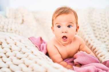 Evdeki kanepede battaniyenin üzerine uzanmış sevimli bir bebek. Yeni doğmuş bebek rahatlıyor ve dinleniyor.