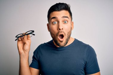 Gözlük takan genç yakışıklı bir adam arka planda saklanıyor. Şaşırmış bir yüzle şoktan korkuyor ve korku ifadesinden korkuyor.