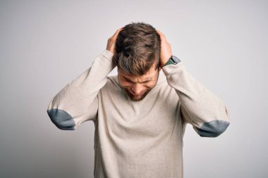 Sakallı, mavi gözlü, başağrısı yüzünden acı çeken, çaresiz ve stresli bir süveter giyen genç yakışıklı sarışın adam. Ellerini başının üstüne koy..