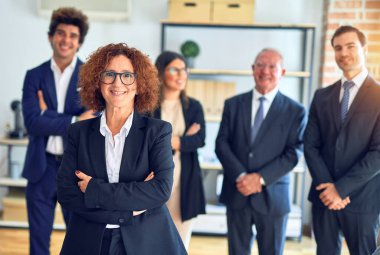 Bir grup iş adamı toplantıda mutlu ve kendinden emin gülümsüyor. Yüzünde gülümsemeyle büroda kameraya bakarken..