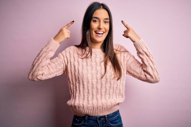 Young beautiful brunette woman wearing casual sweater over isolated pink background smiling pointing to head with both hands finger, great idea or thought, good memory