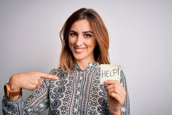 Young beautiful brunette businesswoman overworked holding help reminder paper with surprise face pointing finger to himself