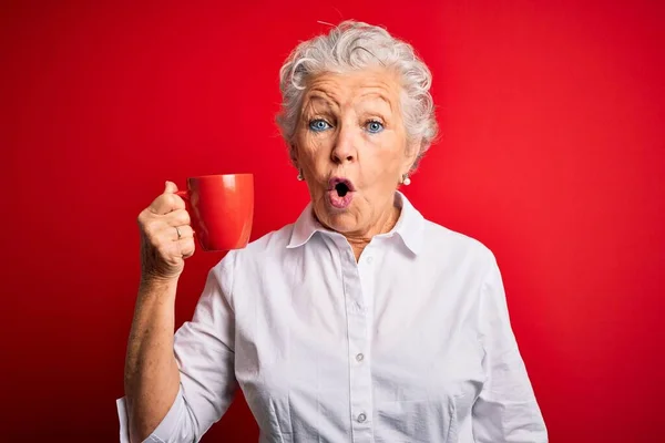 Старшая Красивая Женщина Пьет Кружку Кофе Стоя Изолированном Красном Фоне — стоковое фото