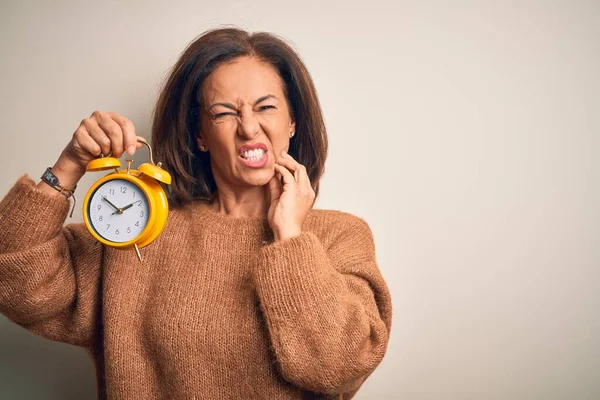 歯の痛みや歯の病気のために痛みを伴う式で手で口に触れる孤立した背景に古典的な目覚まし時計を保持する中世のブルネットの女性 歯医者の概念 — ストック写真
