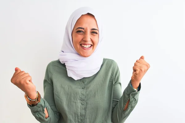 孤立した背景の上に伝統的なイスラム教徒のヒジャーブを身に着けている若い美しいアラブの女性は 腕を上げて開いて目で成功したことに驚いて驚いています 勝者のコンセプト — ストック写真