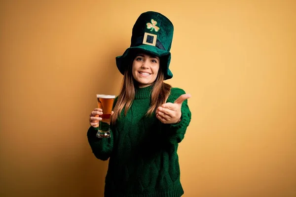 緑の帽子をかぶって若い美しい女性は聖人の公園でビールを飲みます日笑顔陽気な提供ヤシの手援助と受け入れ — ストック写真