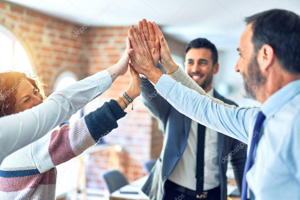 Group of business workers standing with hands together highing five at the office