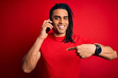 Afrika kökenli Afro Amerikalı genç bir adam Rasta saçlarıyla akıllı telefondan konuşuyor. Şaşırmış bir şekilde kendini işaret ediyor.