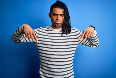 Rastgele çizgili kazak giyen, üzgün ve üzgün görünen, parmaklarıyla yön gösteren, mutsuz ve depresif, genç, Afro-Amerikan bir adam..