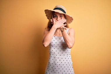 Sarı arka plan üzerine yaz şapkası takan genç, güzel sarışın kadın yanlışlıkla ağızlarını kapatarak şok etti. Gizli konsept.
