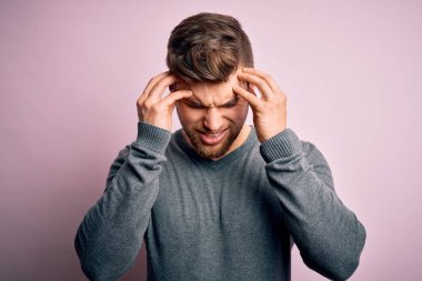 Sakallı, mavi gözlü, elleri başının üstünde, stresten dolayı başı ağrıyan sıradan bir süveter giyen sarışın genç yakışıklı bir adam. Migren ağrısı..