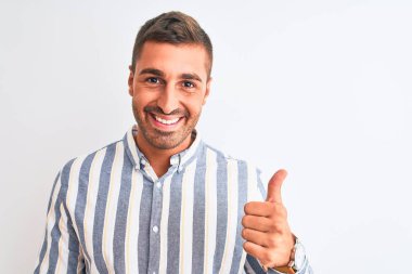 Soyutlanmış arka planda zarif gömlekler giyen genç yakışıklı iş adamı mutlu bir el hareketi yapıyor. Kameraya bakıp başarıyı gösteren ifade onaylanıyor.