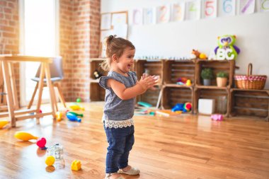 Güzel çocuk, kreşte ayakta alkışlıyor ve gülümsüyor.