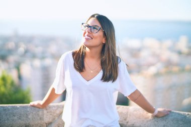 Mutlu ve kendinden emin gülümseyen genç ve güzel bir kadın. Kasaba caddesinde yüzünde gülümsemeyle dikilirken