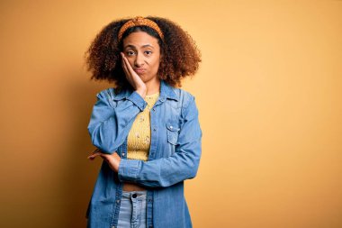 Beautiful african american with afro hair standing over yellow isolated background thinking looking tired and bored with depression problems with crossed arms.