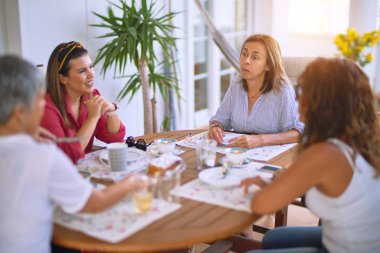 Genç ve güzel bir kız mutlu ve kendinden emin bir şekilde terasta oturmuş bir fincan kahve içiyor.