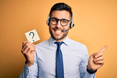 Business operator man with customer service headset from call center showing question mark very happy pointing with hand and finger to the side