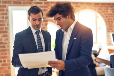 İki yakışıklı iş adamı birlikte çalışıyor. Ofiste duran konuşmalar ve belgeler.