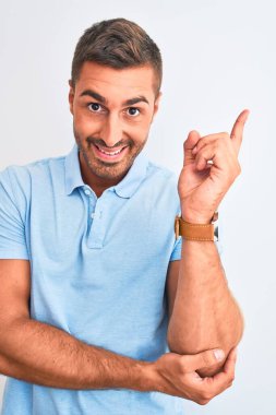 Soyutlanmış arka plan üzerinde mavi tişört giyen genç ve zarif bir adam. Çok mutlu bir şekilde elini ve parmağını kenarı işaret ediyor.