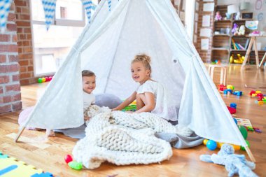 Anaokulundaki bir sürü oyuncağın etrafında battaniyenin üstünde oynayan güzel bebekler.