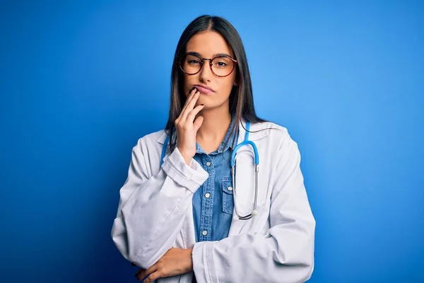 Młoda Piękna Lekarka Nosząca Stetoskop Okulary Niebieskim Tle Myśląca Zmęczona — Zdjęcie stockowe