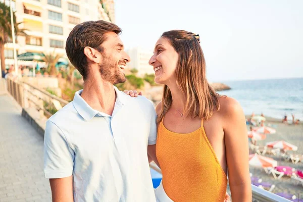 年轻漂亮的夫妇在度假时面带微笑 既快乐又自信 站在海滩上 面带微笑地拥抱着 — 图库照片