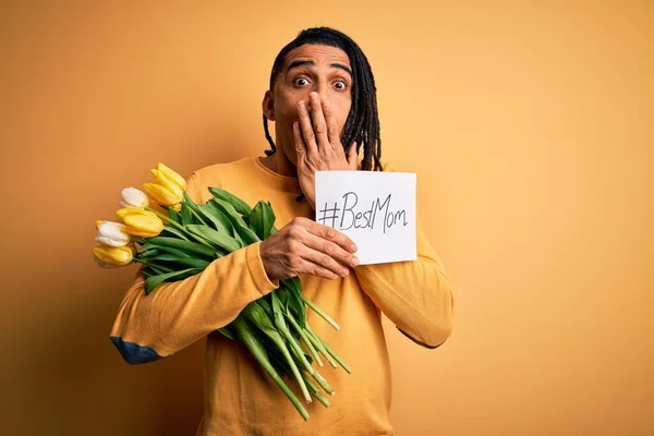 African american man holding best mom message paper and tulips celebrating mothers day cover mouth with hand shocked with shame for mistake, expression of fear, scared in silence, secret concept