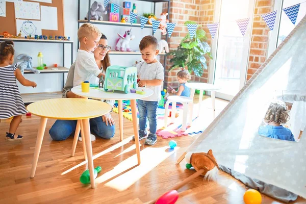 漂亮的老师和一群幼儿在幼儿园玩很多玩具 — 图库照片