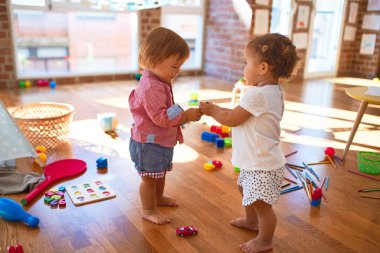 Anaokulunda bir sürü oyuncakla oynayan sevimli çocuklar.