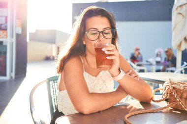 Genç ve güzel bir kadın restoranda oturmuş yaz tatilinin tadını çıkarıyor ve bir bardak bira içiyor.