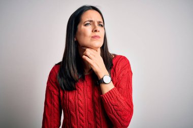 Mavi gözlü genç esmer kadın izole edilmiş beyaz arka planda günlük süveter giyiyor ağrılı boynuna dokunuyor, boğaz ağrısı, grip salgını ve enfeksiyon kapmış.