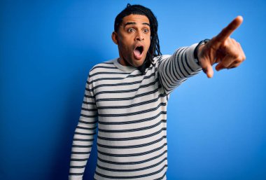 Rastgele çizgili süveter giyen Afro-Amerikan genç, yakışıklı afro bir adam. Parmağıyla işaret ediyor. İleriye şaşırmış, ağzı açık, ön tarafta bir şey var.