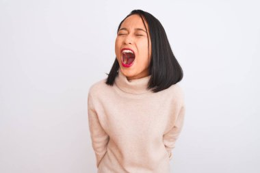 Balıkçı yaka kazak giyen genç Çinli kadın izole edilmiş beyaz arka planda öfkeli ve öfkeli bir şekilde bağırıyor. Öfkeyle bağırıyor. Öfke ve agresif kavram.