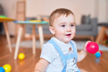 Anaokulunda küçük renkli toplarla oynayan güzel bir çocuk.