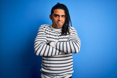 Rasta desenli çizgili süveter giyen, kuşkucu, gergin ve yüzünde çapraz kollu tasvip etmeyen genç Afro Amerikalı Afro adam. Negatif kişi.