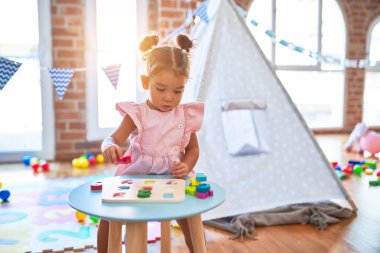 Anaokulunda matematik oyunu oynayan genç ve güzel bir çocuk.