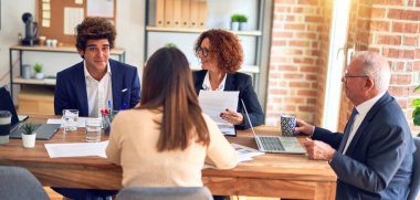 Bir grup iş adamı mutlu ve kendinden emin gülümsüyor. Ofiste birlikte çalışırken gülümseyerek konuşmak..