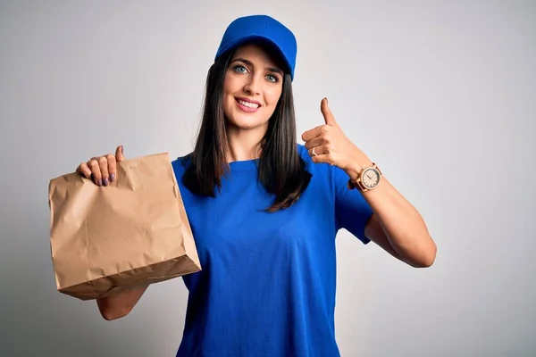 大きな笑顔で幸せな食べ物と紙の袋を保持キャップを身に着けている青い目を持つ若い配信女性はOkサインをします 指で親指アップ 優れたサイン — ストック写真