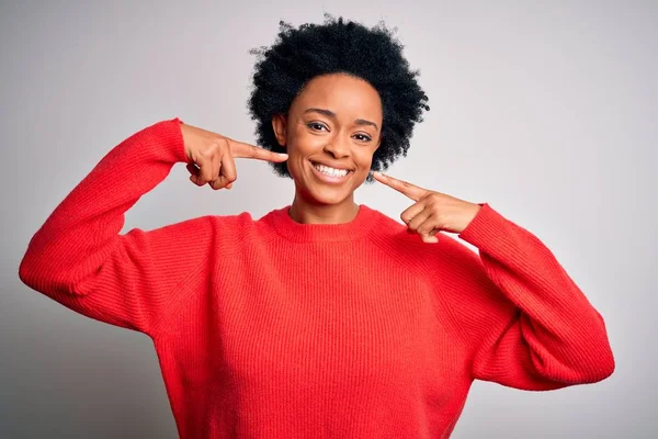 赤いカジュアルなセーターを着て巻き毛を持つ若い美しいアフリカ系アメリカ人アフロ女性は 陽気な表情と指の歯と口で指して笑っています 歯科衛生の概念 — ストック写真