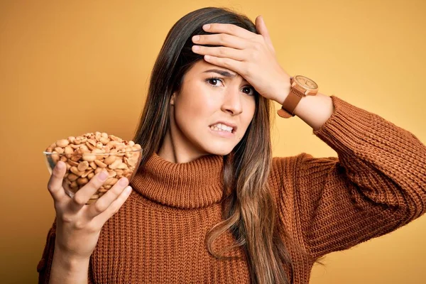 Young Beautiful Girl Holding Bowl Salty Peanuts Standing Yellow Background — Stock Photo, Image