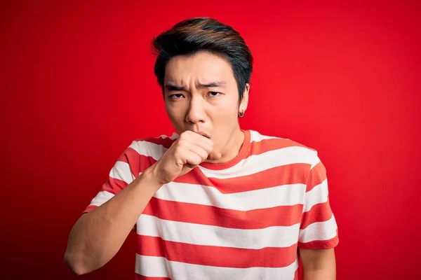 若いハンサムな中国人男性がカジュアルな縞模様のTシャツを着て 寒さや気管支炎の症状として咳をしない赤の背景感の上に立っている ヘルスケアの概念 — ストック写真