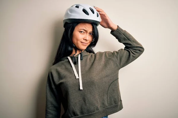 年轻美丽的中国女人 戴着自行车头盔 披着孤立的白色背景 对问题感到困惑和好奇 拿不定主意 手拿着头思考 沉思的概念 — 图库照片