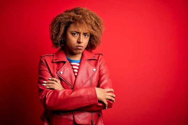 カジュアルな赤いジャケットを身に着けている巻き毛を持つ若い美しいアフリカ系アメリカ人アフロ女性は懐疑的で緊張し 両腕を組んで顔に不承認式 負の人 — ストック写真