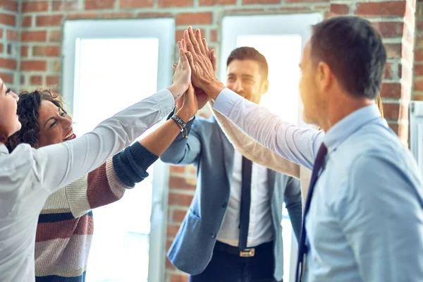 Group of business workers standing with hands together highing five at the office