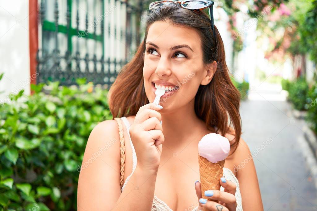 Young beautiful woman eating ice cream cone on a sunny day of summer on holidays